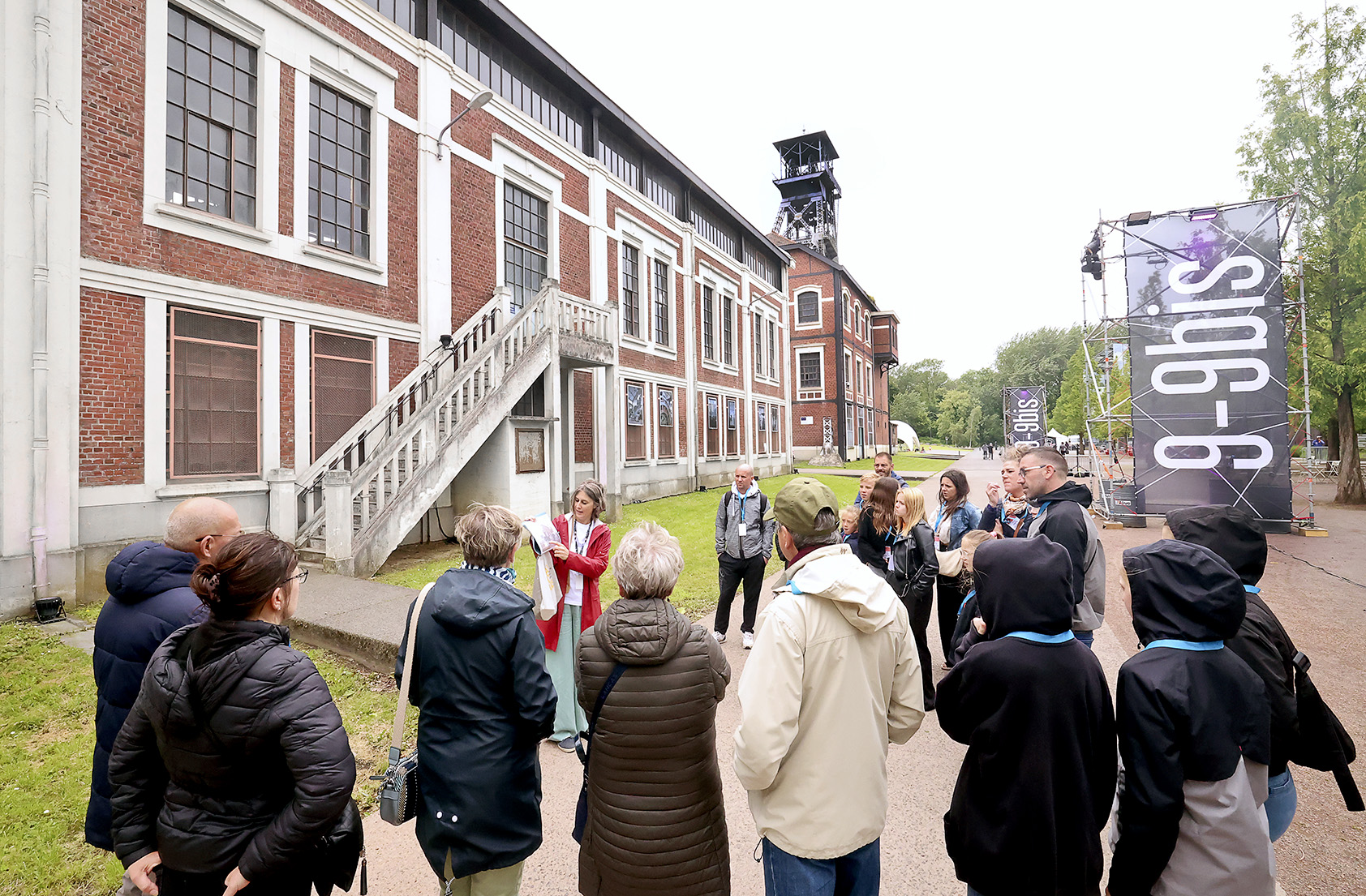 Visite de l'esplanade du site minier du 9-9bis à un groupe de personnes par une médiatrice du patrimoine